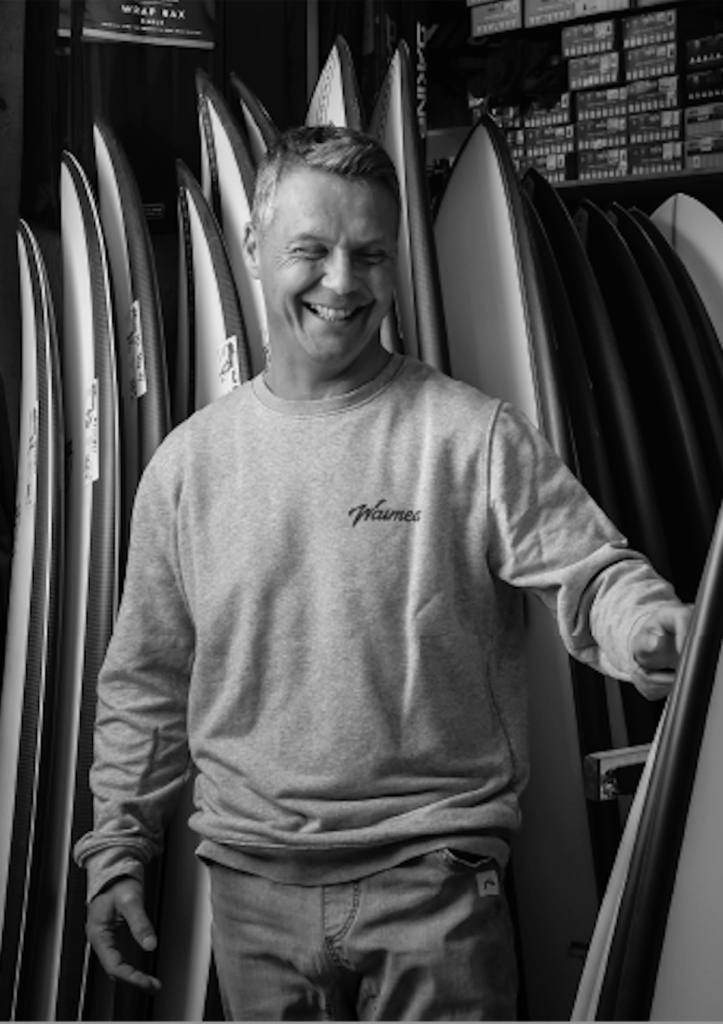 Xabi Anton, propriétaire de Waimea Surfshop à Anglet, plage Les Sables d'Or au Pays basque, entouré de planches de surf.